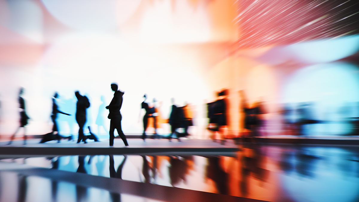 Silhouttes of people walking in front of a multicoloured background